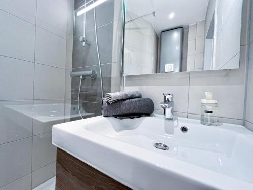 ein weißes Bad mit einem Waschbecken und einer Dusche in der Unterkunft LE PARADIS FISCAL, 5min Bâle, parking privé in Saint-Louis