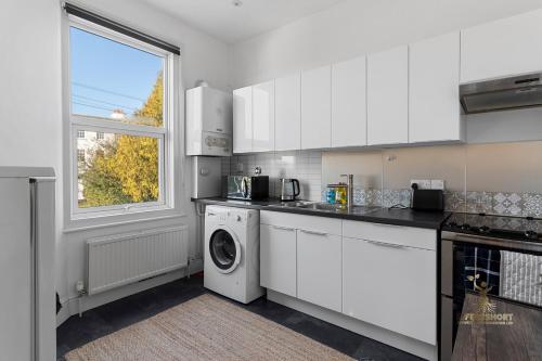 una cucina con mobili bianchi, lavatrice e asciugatrice di Central Exeter Apartment (Kimberley 1A) a Exeter