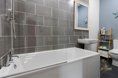 ein Badezimmer mit einer weißen Badewanne und einem Waschbecken in der Unterkunft Central Exeter Apartment (Kimberley 1A) in Exeter