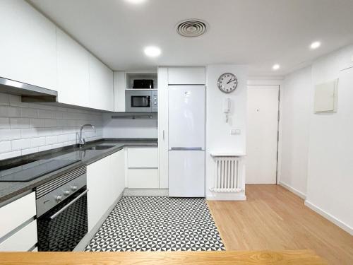 a kitchen with white cabinets and a clock on the wall at AZ El Balcón a la Basílica III - en plena Plaza del Pilar! in Zaragoza