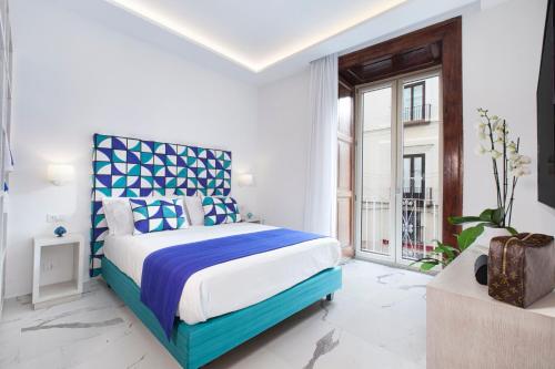 - une chambre avec un lit bleu et blanc et une fenêtre dans l'établissement Sorrento Lux Suite, à Sorrente