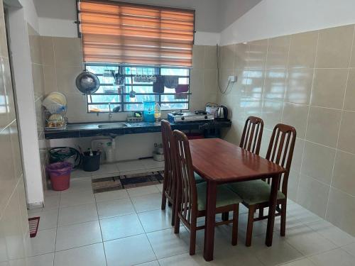een keuken met een houten tafel en stoelen in een kamer bij Sobey Laris Homestay RP in Pasir Mas