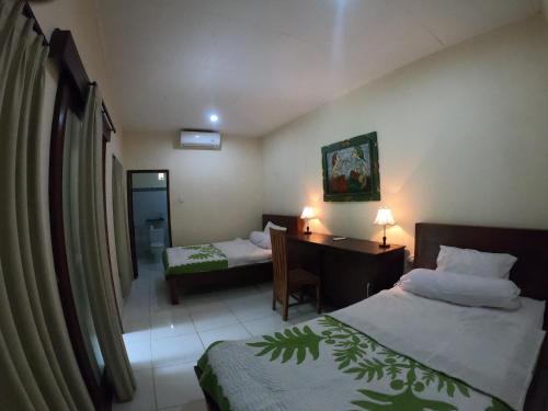 Habitación de hotel con 2 camas, escritorio y escritorio. en Honey Home Stay en Canggu