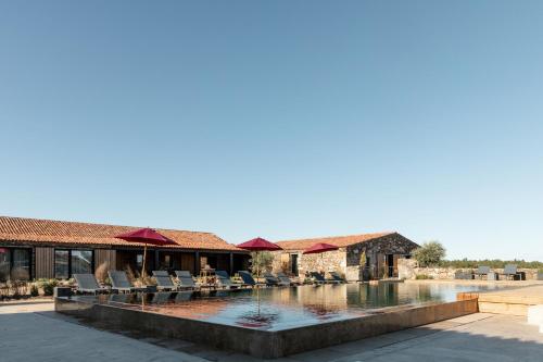 a swimming pool with chairs next to a house at Herdade dos Abegões in Salvaterra do Extremo