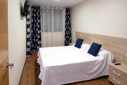 een slaapkamer met een wit bed met blauwe kussens bij Ancla Spaces EGVT-436-CS no vista al mar in Vinarós