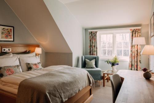 a bedroom with a bed and a chair and a window at Engø Gård Hotel & Restaurant in Tjøme