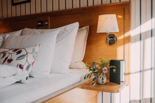 a bedroom with a bed with white pillows and a lamp at Engø Gård Hotel & Restaurant in Tjøme