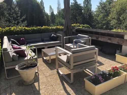 een patio met een bank, stoelen en planten bij La Rozeliere 