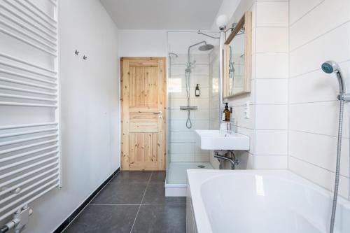 ein Badezimmer mit einer Badewanne, einem Waschbecken und einem Spiegel in der Unterkunft Ruhig Hell Wohnen im Grünen füßläufig zum Wasser 25min bis Flughafen in Berlin
