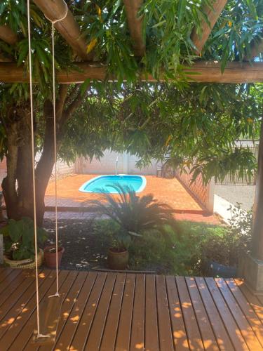 a swimming pool in a yard with a wooden deck at Suíte Maciel in Foz do Iguaçu