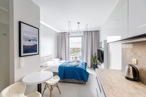 a white living room with a bed and a table at Balticus Apartamenty Standard Promenada Gwiazd 14 in Międzyzdroje