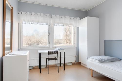 Schlafzimmer mit einem Schreibtisch, einem Bett und einem Fenster in der Unterkunft Näsbygården in Storvik