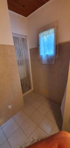 uma casa de banho com chuveiro, janela e piso em azulejo em CHEZ ISABELLE em Luri