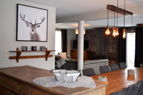 a living room with a table with a deer on the wall at Gîte Wellness "Le Poirier" in Durbuy