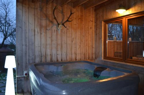 a bath tub in a room with a wooden wall at Gîte Wellness "Le Poirier" in Durbuy