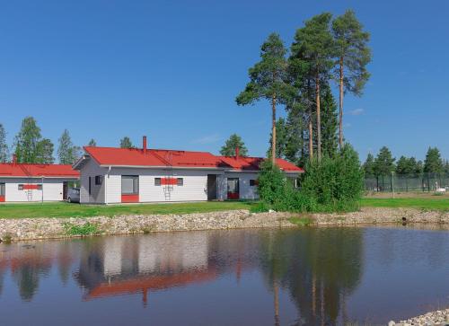 uma casa branca com um telhado vermelho ao lado de um lago em Holiday Club Katinkulta Superior Apartments em Vuokatti