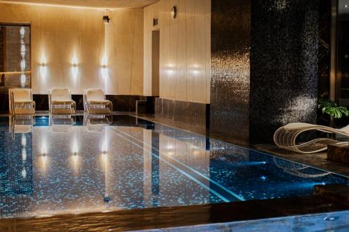 un vestíbulo con una piscina con sillas. en Hotel Monopol en Wroclaw