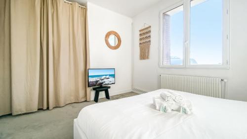 a white bedroom with a bed and a tv at HOMEY HANNA - Au pied du tram / Parking gratuit / Balcon privé / Wifi gratuit in Annemasse