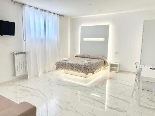 a bedroom with a bed in a white room with marble floors at IL VIAGGIATORE RELAIS SUL MARE in Gaeta