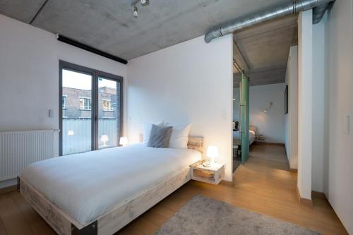 a bedroom with a white bed and a large window at London 993 Loft 402 in Antwerp