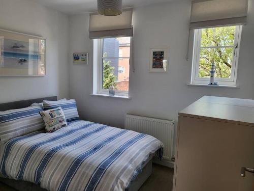 a small bedroom with a bed and two windows at Stones Throw-near harbour & beach Pet Friendly in Weymouth