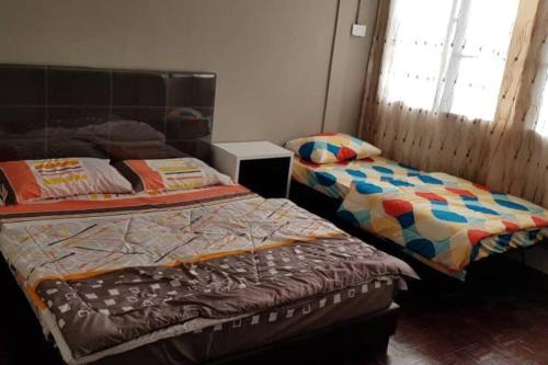a bedroom with two beds and a window at J & I Homestay in Sibu