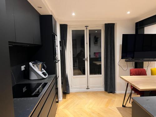 une cuisine avec des armoires noires, une télévision et une table dans l'établissement Nantes Hyper Centre - Decré Bouffay - Rue Piétonne, à Nantes