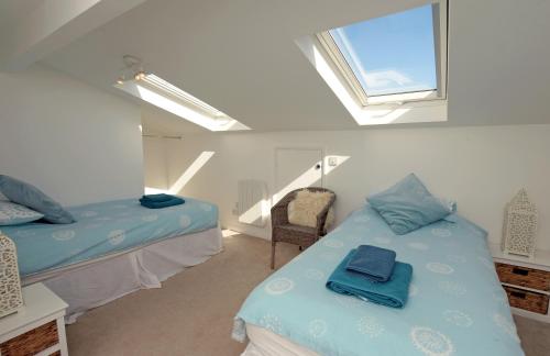 a attic bedroom with two beds and a window at Gone to the Beach - Sea Views Direct Beach Access in Saundersfoot