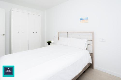 um quarto branco com uma cama grande e lençóis brancos em Sinda Apartment El Puertillo em Arucas