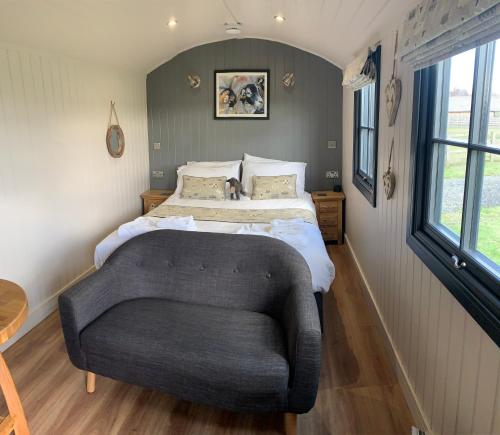 約克的住宿－Springwood Shepherd Huts Glamping York，一间卧室配有一张床和一张沙发