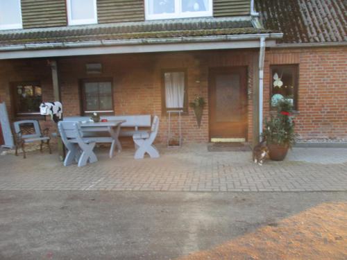 un patio con una mesa y un gato frente a una casa de ladrillo en Ferienwohnung 1 - a76809, en Groß Vollstedt