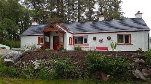 a small white house with a red door at Back2Roots - Beautifully Restored Cottage, Doochary in Doochary