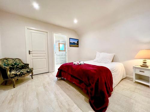 a bedroom with a bed with a red blanket and a chair at Le GRANNEC in Trégastel