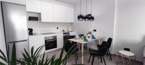 una cucina con armadi bianchi, tavolo e sedie di Apartment Las Terrazas Costa Adeje Ocean View ad Adeje