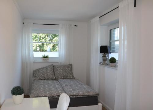 a small bedroom with a bed and two windows at Ferienwohnung Am Schippstroth in Wiefelstede