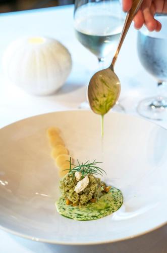 a person holding a spoon with a dish on a plate at Engø Gård Hotel & Restaurant in Tjøme