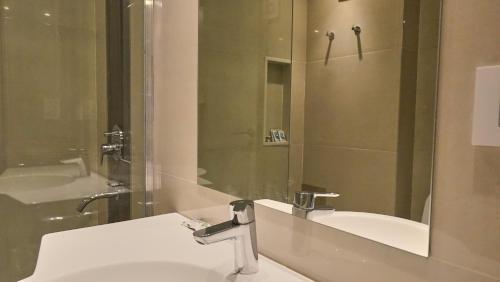 uma casa de banho com um lavatório, um espelho e uma banheira em Ferrol Apart Hotel em Funes
