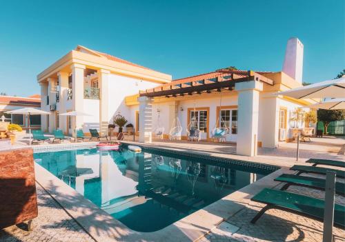 a villa with a swimming pool in front of a house at CLIFF Surf House in A dos Cunhados