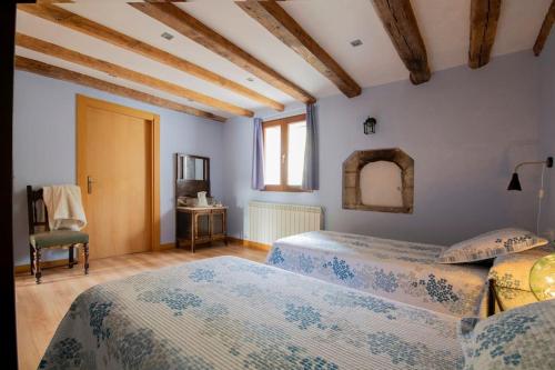 a bedroom with two beds and a table and a chair at Casa rural Enekoizar in Abaurrea Alta