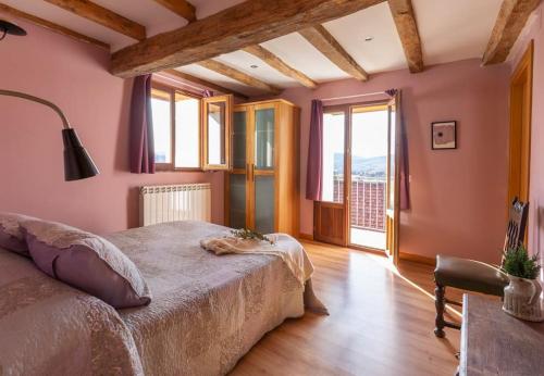 1 dormitorio con paredes rosas, 1 cama y ventana en Casa rural Enekoizar, en Abaurrea Alta