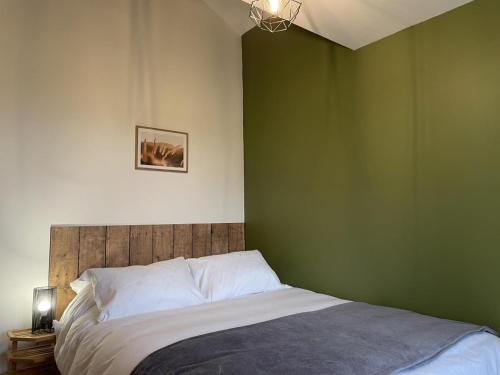 una camera da letto con una parete verde e un letto di Ancienne bergerie rénovée avec piscine et grand jardin en Auvergne - FR-1-489-411 a Durdat-Larequille