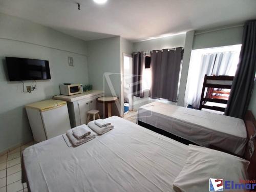 a hotel room with two beds and a microwave at CTC Araras Centro in Caldas Novas