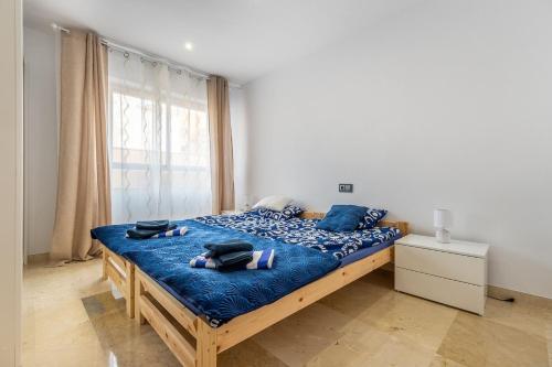 sypialnia z łóżkiem z niebieskimi prześcieradłami i oknem w obiekcie Apartament Claro w mieście Torrevieja