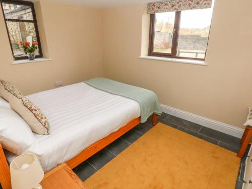 a small bedroom with a bed and two windows at Green Grove Barn in Carmarthen