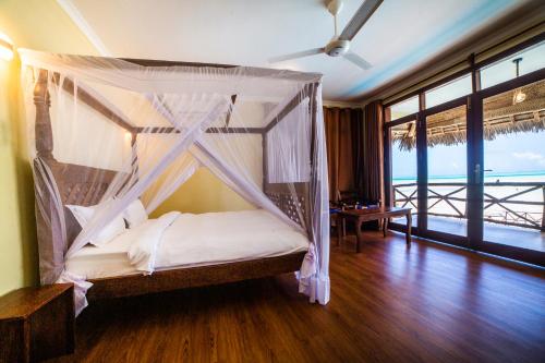 a bedroom with a canopy bed with a view of the ocean at Mahi Mahi Beach Hotel in Jambiani