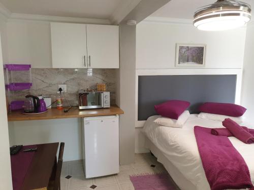 a room with a bed and a kitchen with purple pillows at The Haven: Make our Home your Home in Estcourt