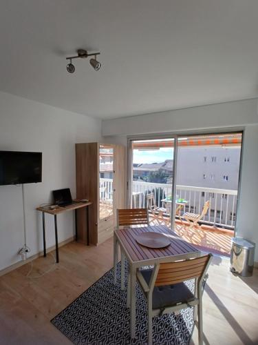 a living room with a table and a balcony at Studio Tout à Pied - Vue Sur Mer in Saint-Aygulf