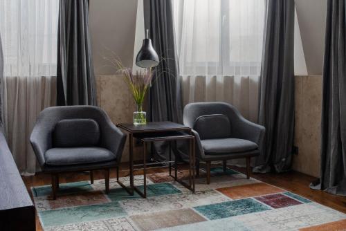 a living room with two chairs and a table with a vase at Hotel Monopol in Wrocław