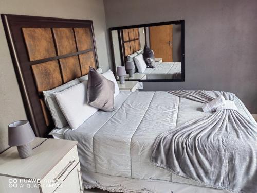 a bedroom with a large bed and a mirror at Kgakgamela road lodge in Driekop