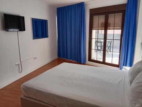 a bedroom with a bed and a window with blue curtains at Hotel Trafalgar in Jerez de la Frontera